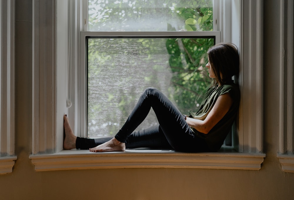 a woman sitting on a window sill