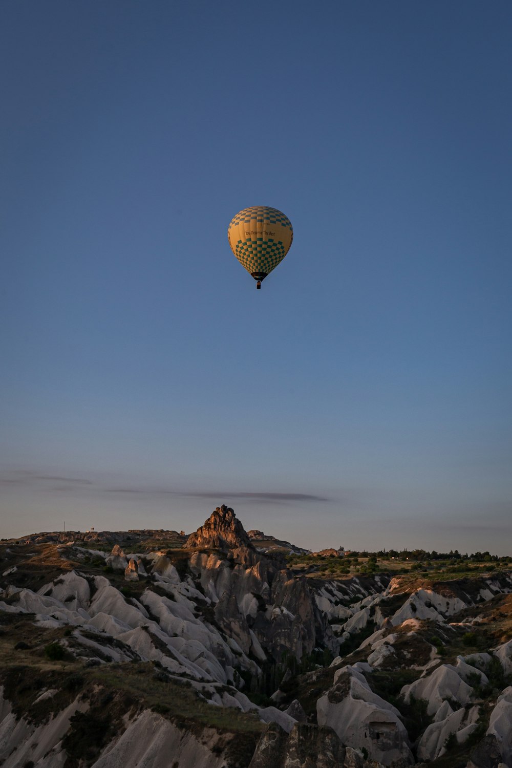 a hot air balloon flying over a rocky landscape