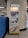 A vending machine placed between a tiled wall and a large column in a subway station. The machine has a bright display screen with text and card images, multiple buttons, and a section for card transactions. It is branded with the 'Octopus' logo and slogan 'Making Everyday Life Easier.'