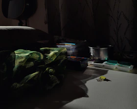 A dimly lit studio with scattered art supplies and soft shadows.