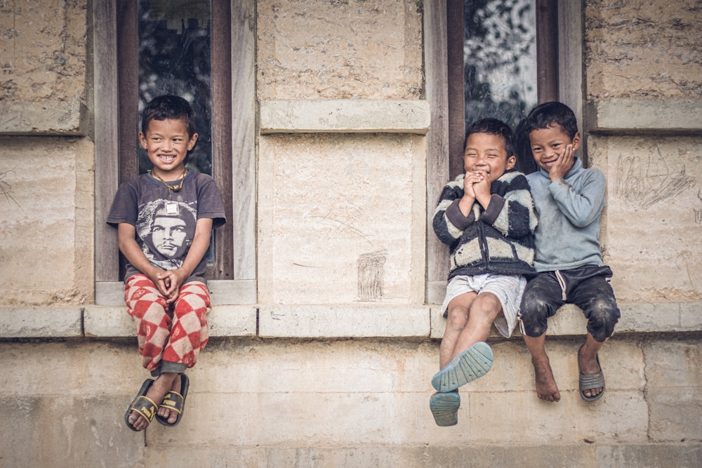 a group of children sitting on a window ledge