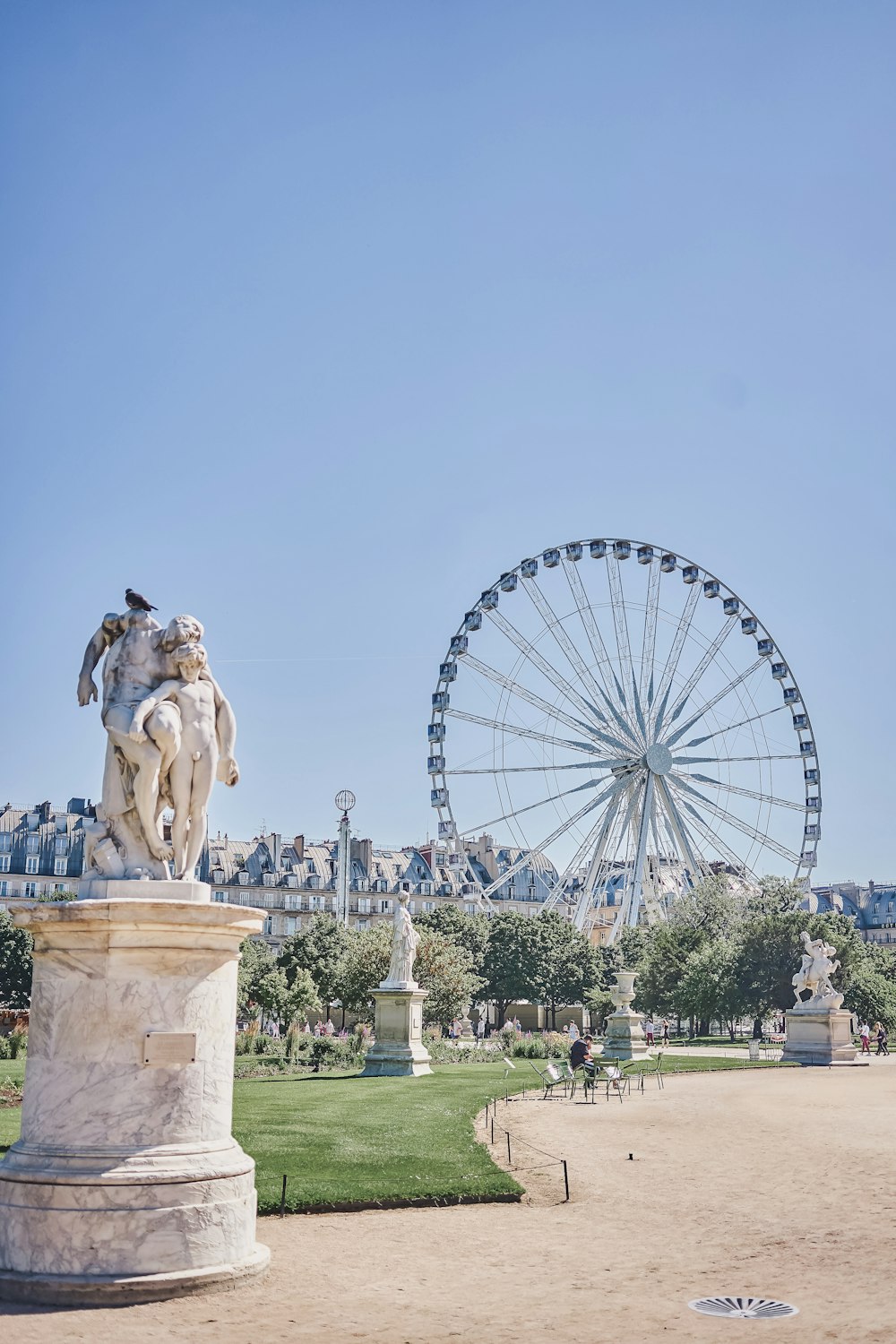 a statue of a person and a ferris wheel in the background