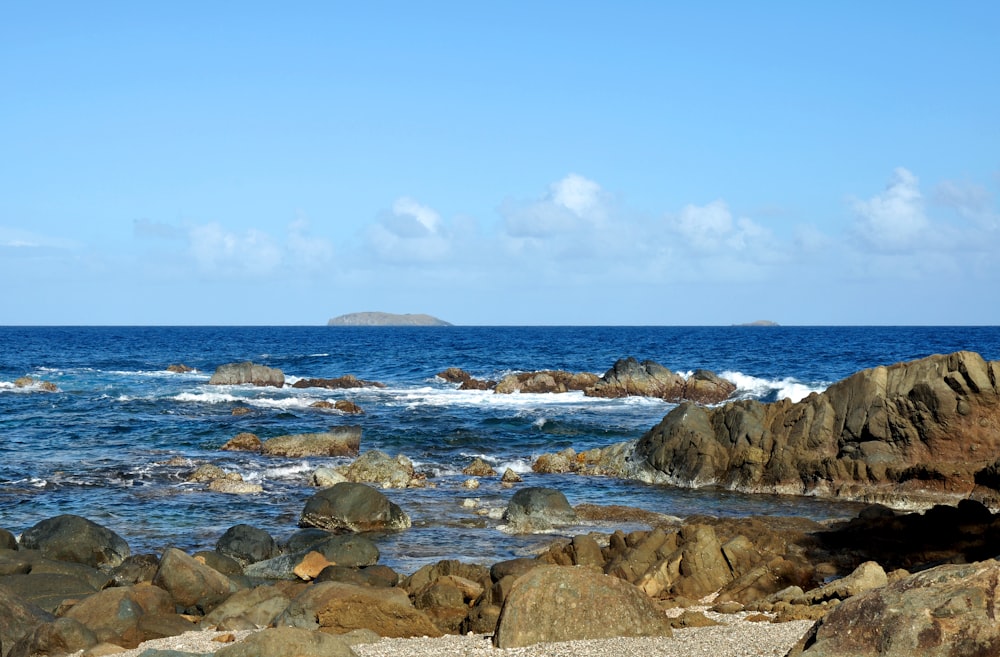 a rocky beach with a large body of water in the background