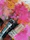 Three paintbrushes with different bristle types rest on a palette covered with thick, textured layers of paint in various colors. The paint is applied in broad, swirling strokes, creating an abstract and vibrant background.