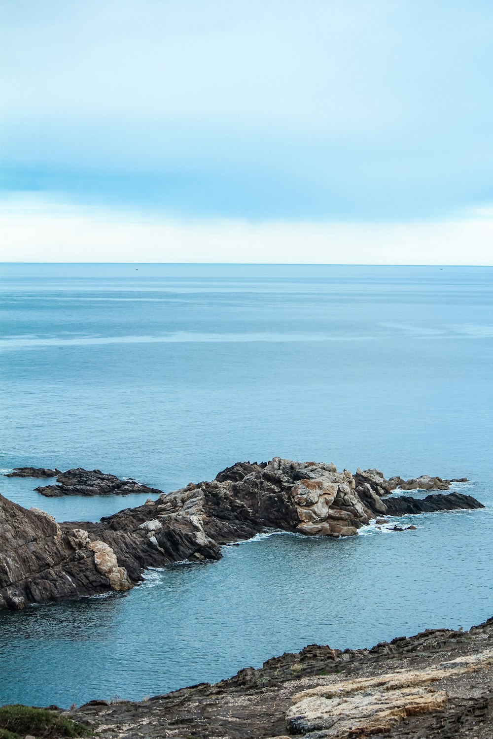 a rocky beach with a body of water in the background