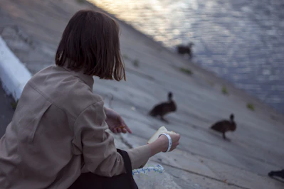 a person sitting on a dock looking at ducks