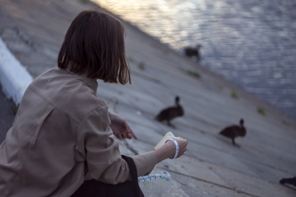 a person sitting on a dock looking at ducks