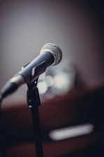 Close-up of a microphone with a blurred background of a live streaming setup.