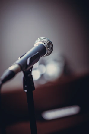 Close-up of a microphone with the Abhay Media logo softly blurred in the background.