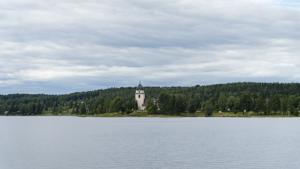 a body of water with trees and a building in the background