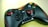 A black gaming controller with red accents rests on a light surface. It features two thumb sticks, a D-pad, and several colorful buttons, including buttons labeled START and BACK, and a logo reading 'Red Star'.