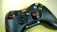A black gaming controller with red accents rests on a light surface. It features two thumb sticks, a D-pad, and several colorful buttons, including buttons labeled START and BACK, and a logo reading 'Red Star'.