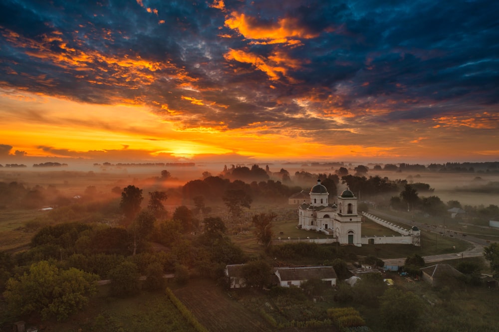 a building in a valley with trees and a sunset