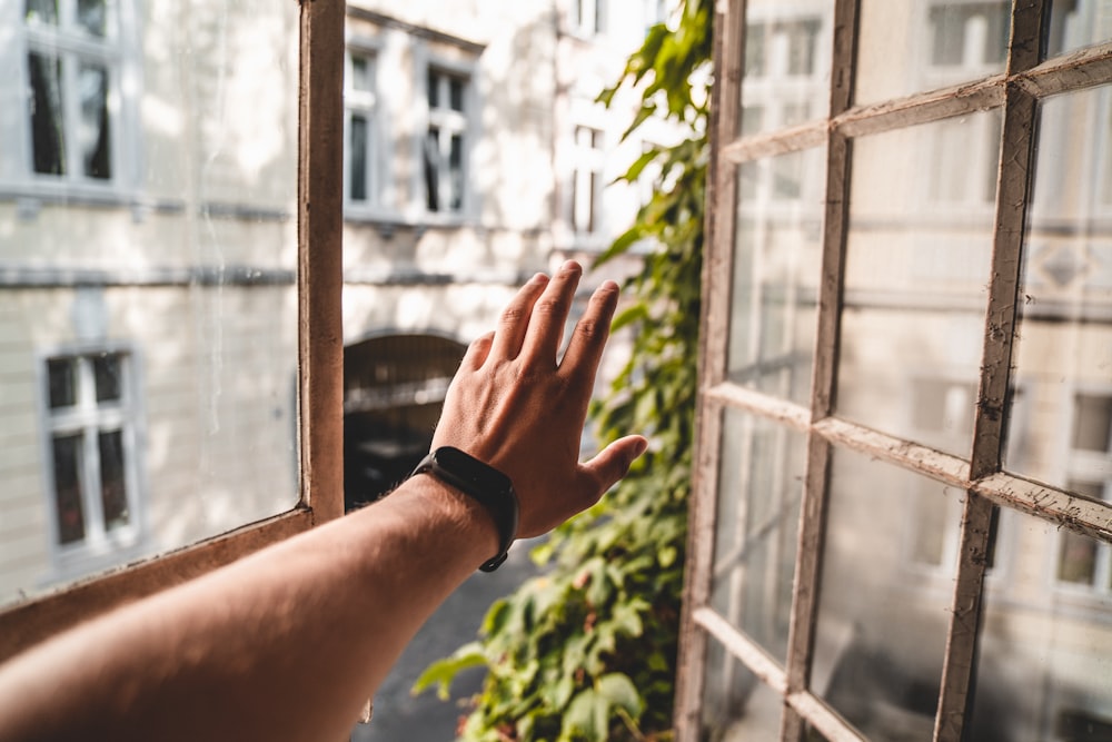 a hand reaching out to a window