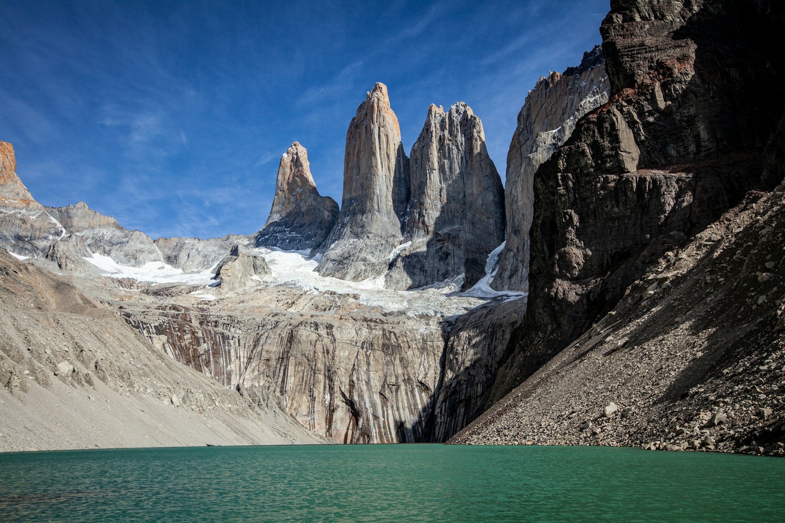 The rock towers of Torres del Paine rising above a green-blue lake under a clear blue sky