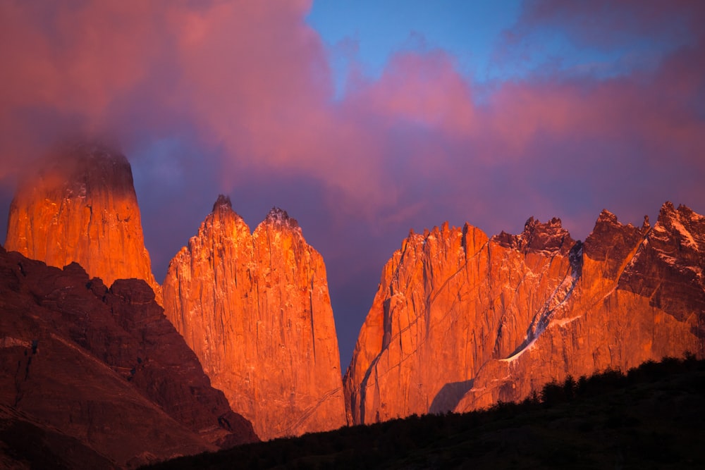 a rocky mountain with a pink and purple sky