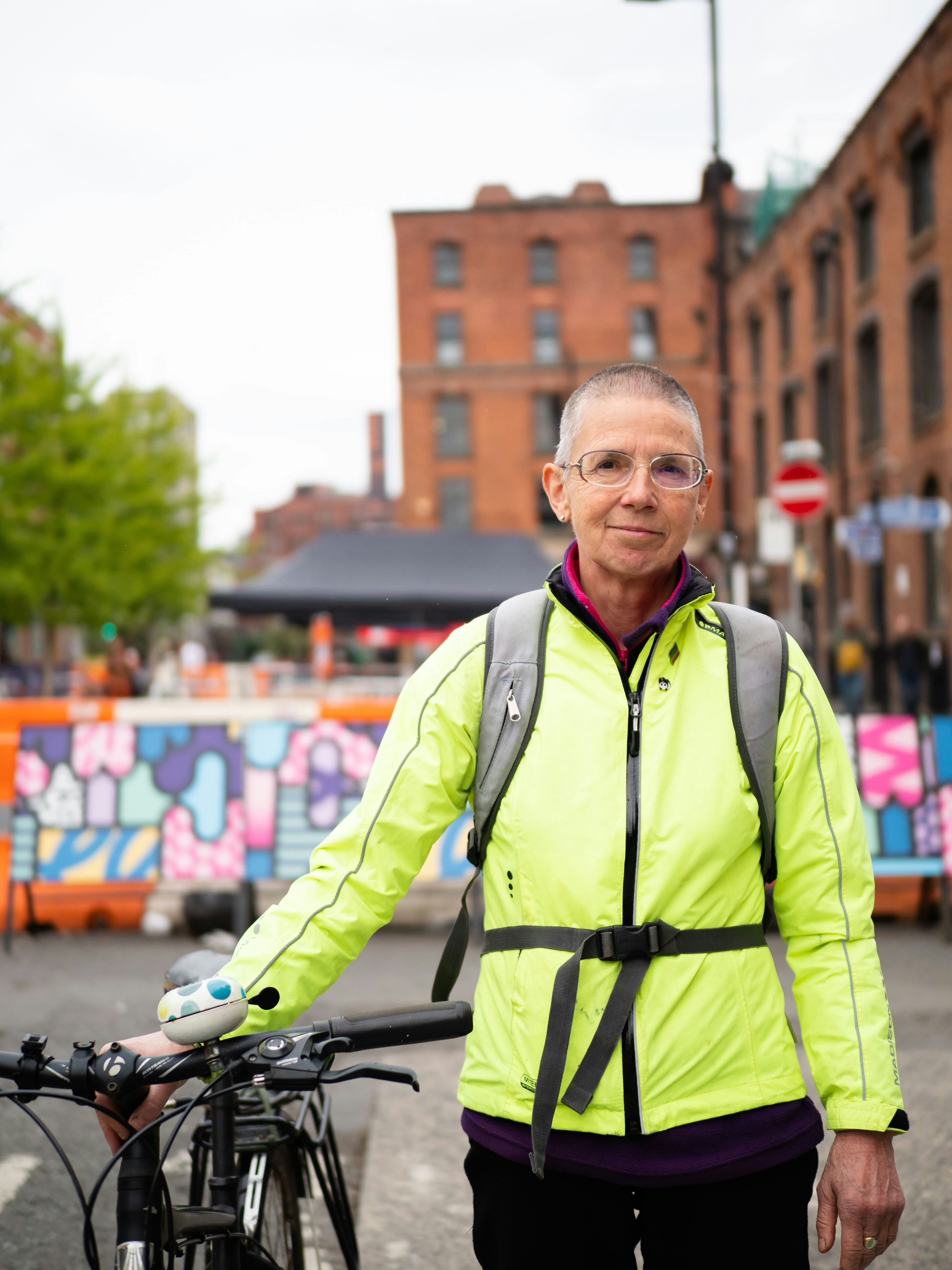 An older woman with a hi visibility jacket on.