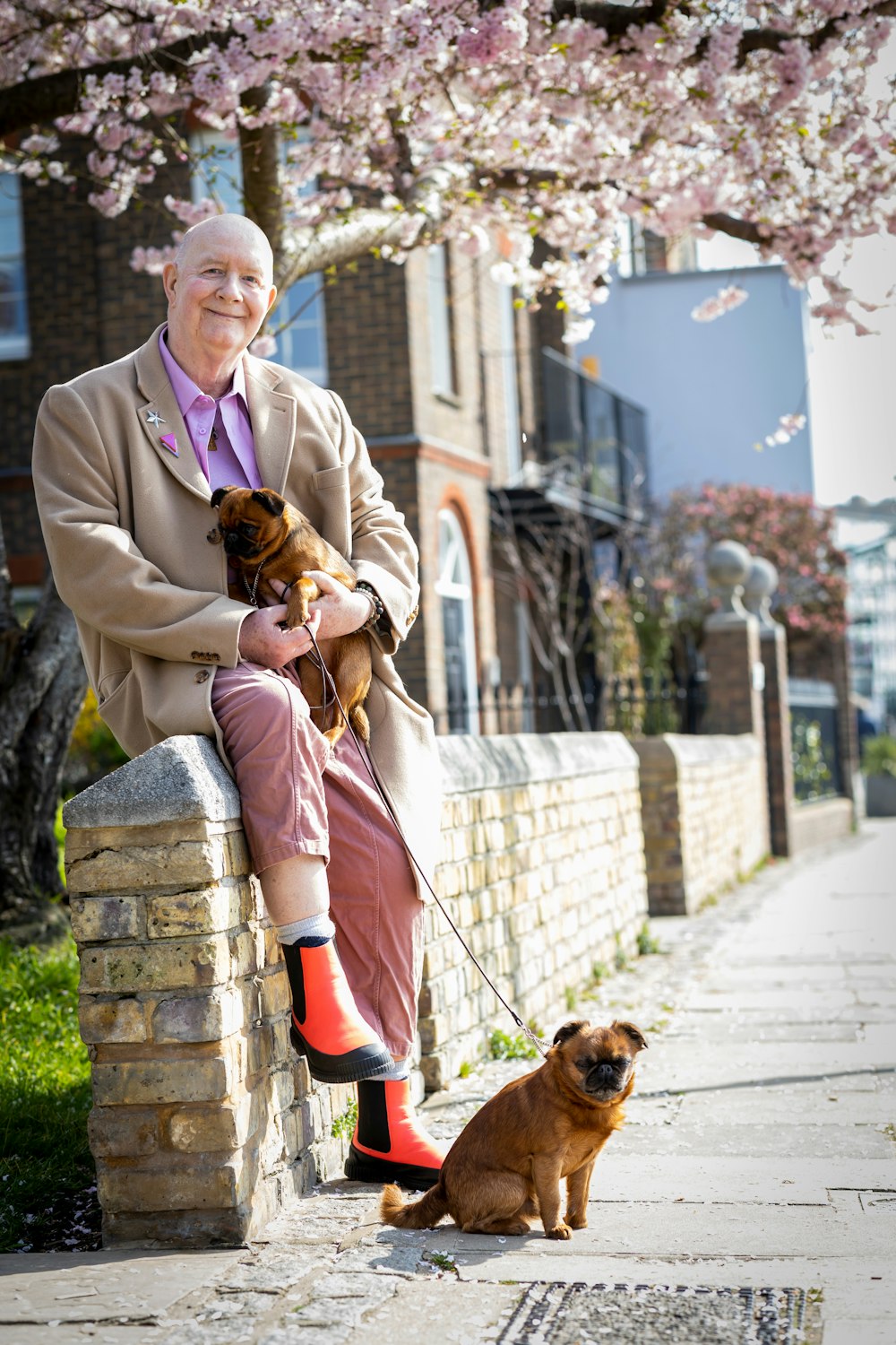 a person in a suit and red boots holding a dog