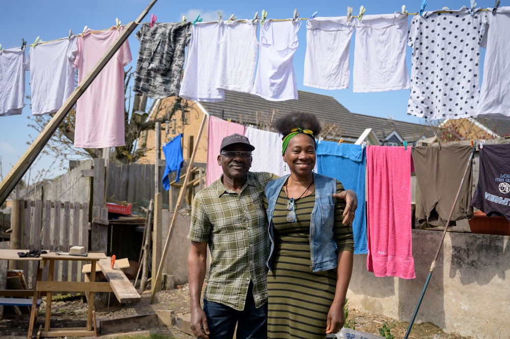 a man and woman posing for a picture in front of a clothes line