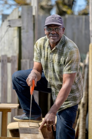 Close-up of hands measuring and cutting wood for a custom fence section.