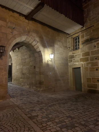 An ancient Damascus alleyway with intricate stonework, softly lit by olive green lanterns at dusk.