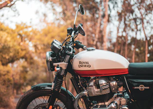 Close-up shot of a vintage Royal Enfield motorcycle gleaming under soft sunlight.