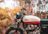 Photo of Amit Raj smiling beside his restored Royal Enfield in an urban Indian street