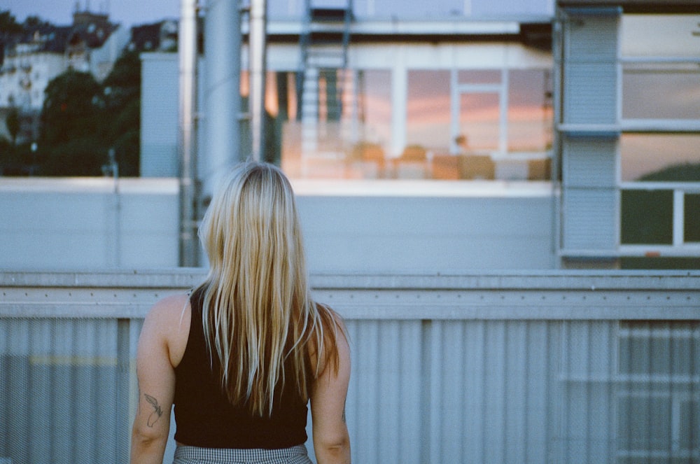 a woman standing in front of a railing looking out at a city