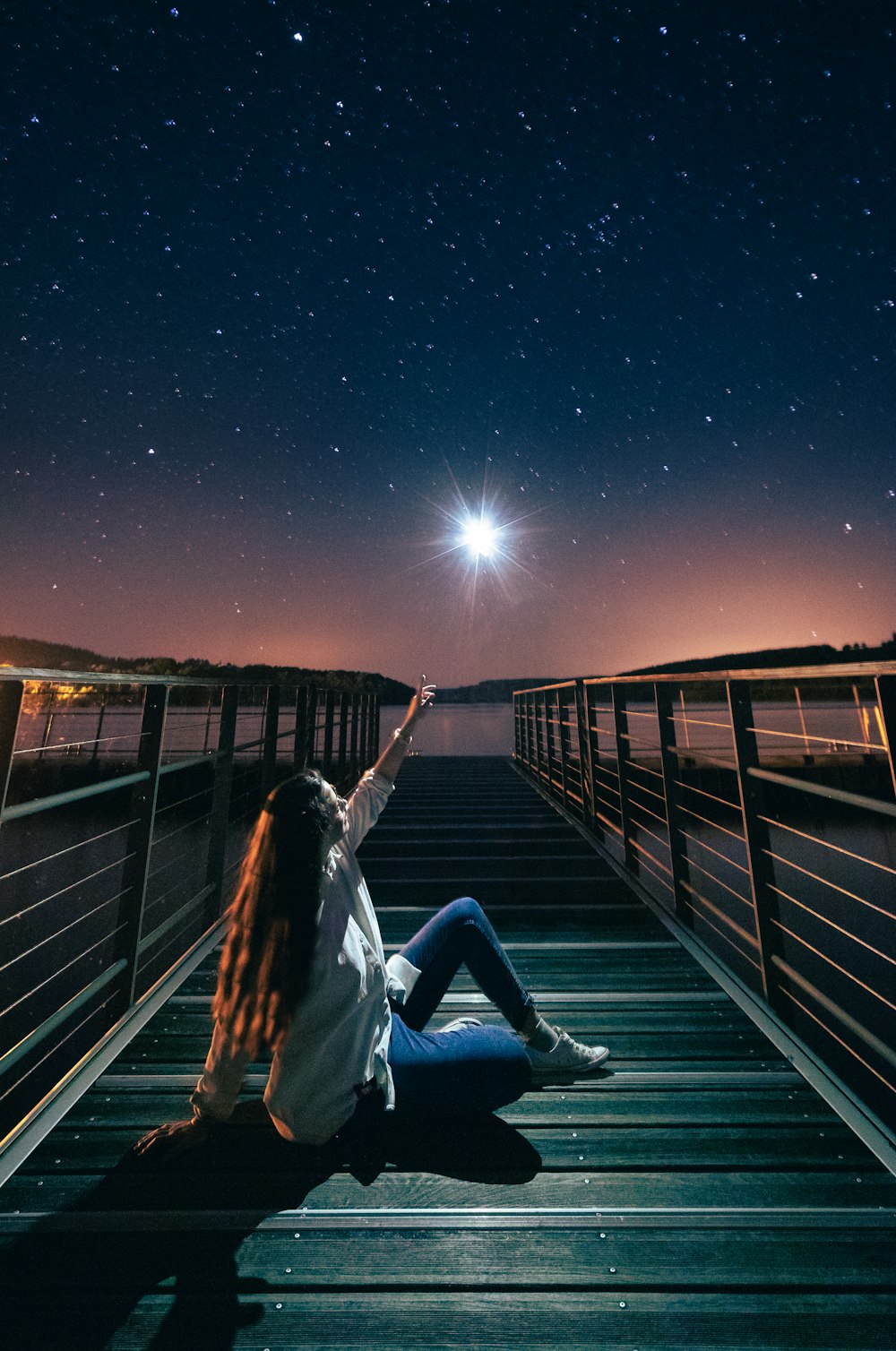 a person sitting on a bridge with the stars in the sky