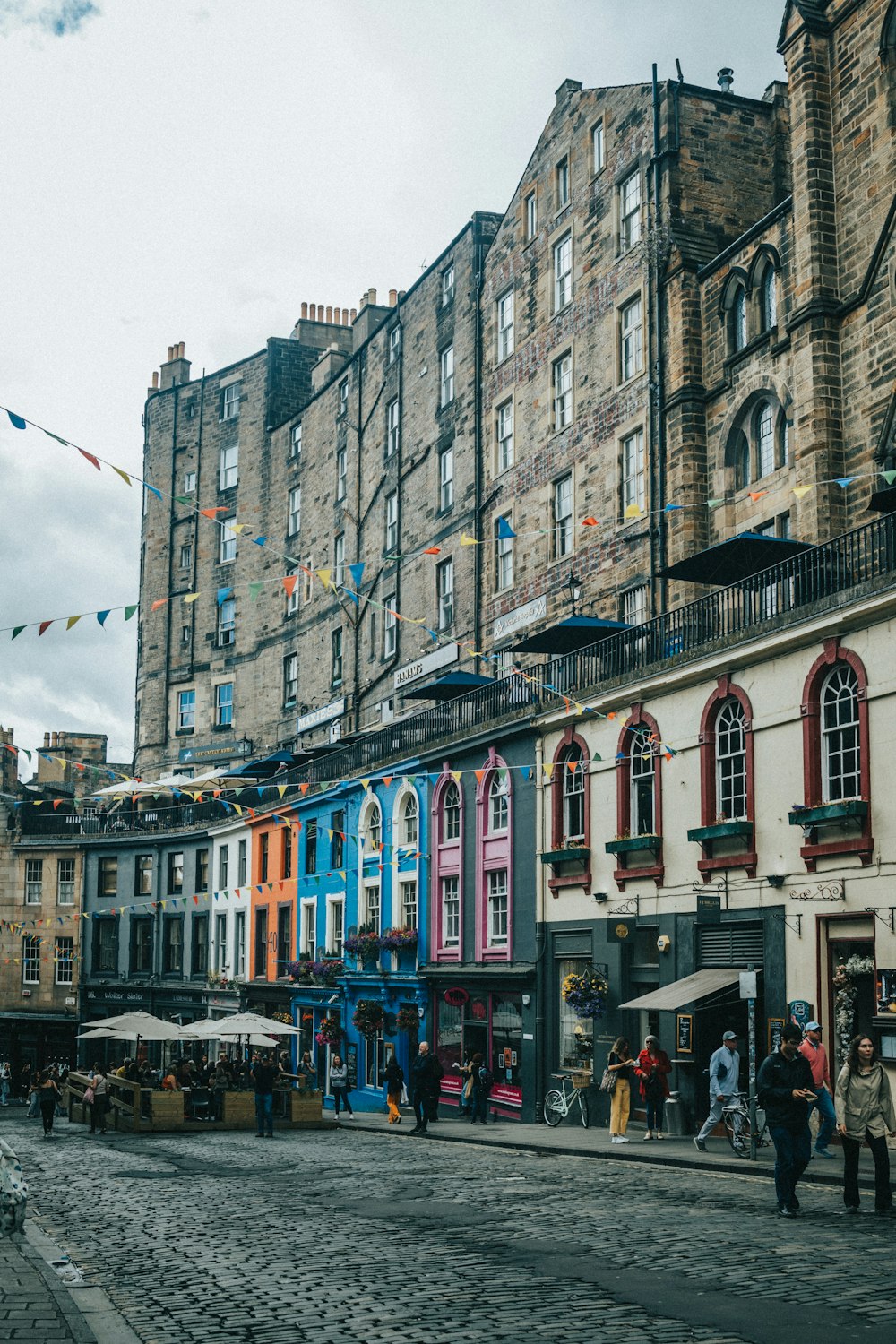 a group of people walking on a street next to a row of buildings