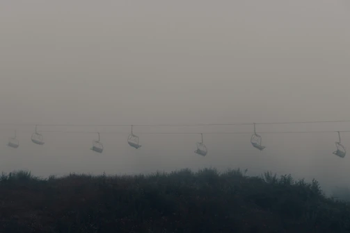 A surreal scene of a chair suspended in fog, surrounded by tangled wires and shadows.