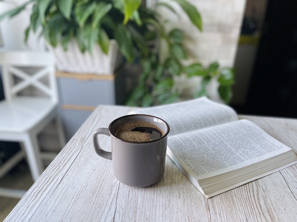 A neatly arranged coffee nook featuring a Calm Brew Mug, a small plant, and a book.