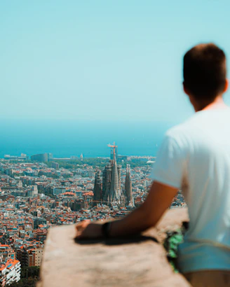 a man sitting on a ledge overlooking a city