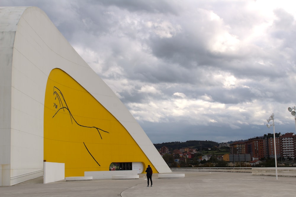 a person walking next to a large white and yellow sculpture