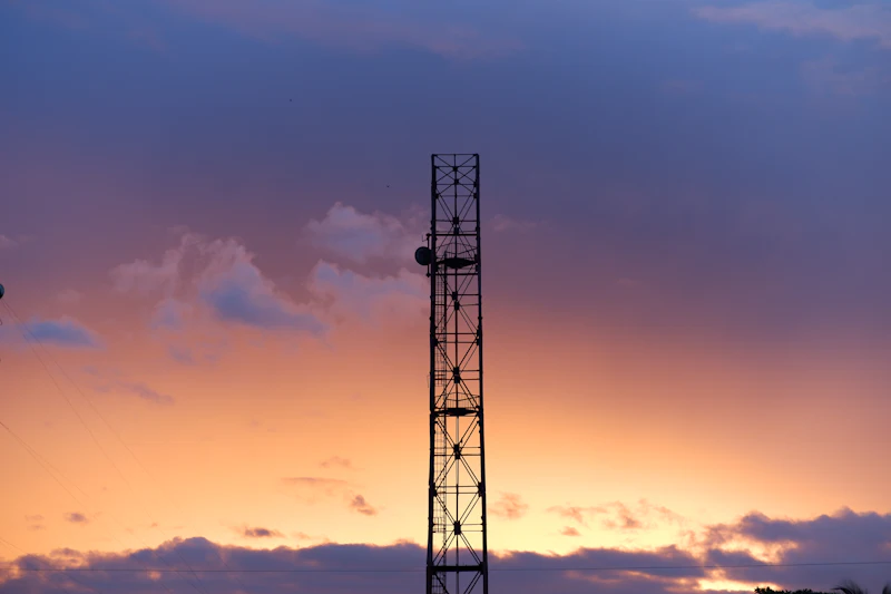 Mobile network tower against a purple and orange sunset