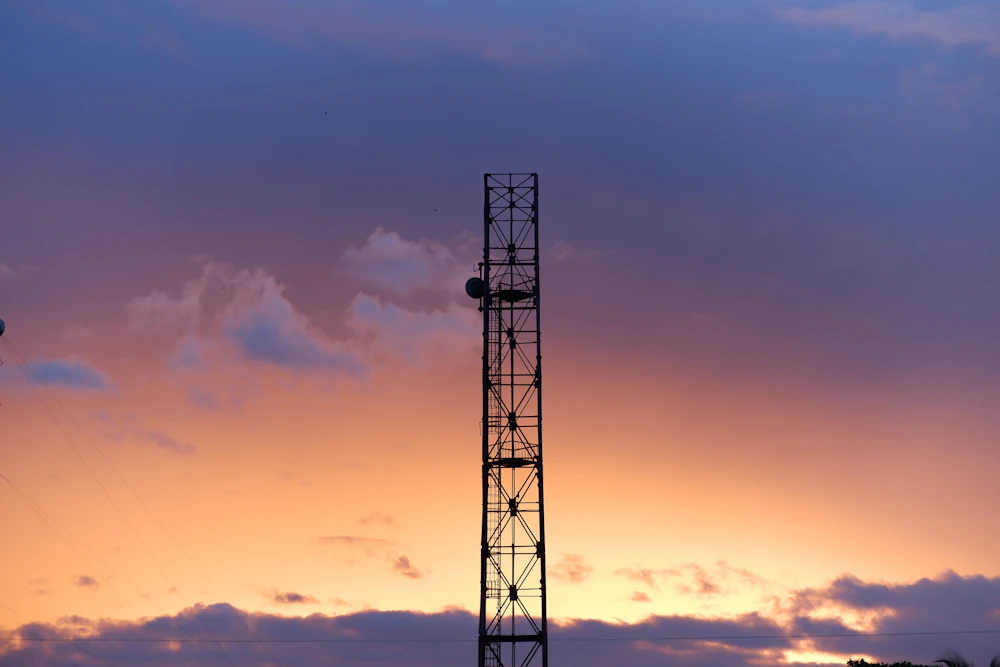 A single lattice tower against a pink and orange sunset