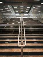 A wide metal staircase with clean lines leading to a bright mezzanine.