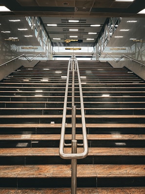 A wide metal staircase with clean lines leading to a bright mezzanine.