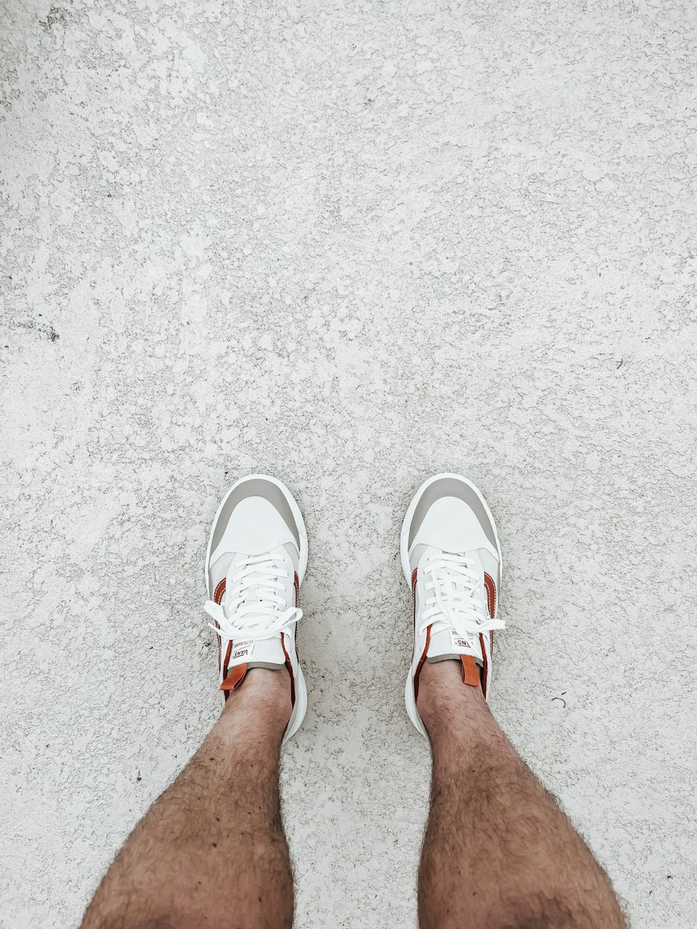 a person's legs with white shoes on