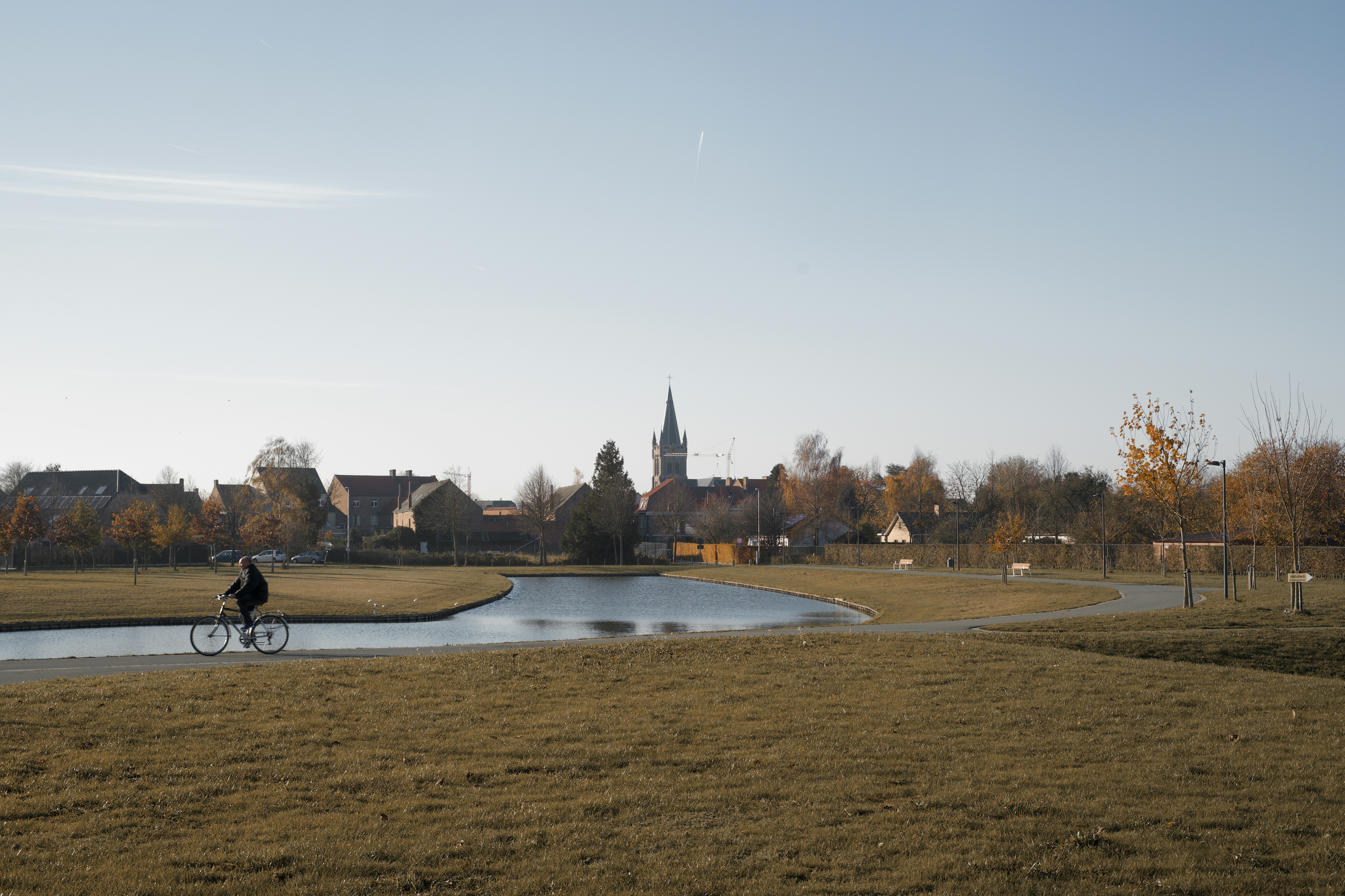 Una persona montando en bicicleta en un camino de tierra cerca de un estanque