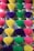 Multiple bundles of incense sticks arranged vertically in rows, with each bundle consisting of sticks dyed different vibrant colors such as pink, yellow, purple, and green.