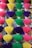 Multiple bundles of incense sticks arranged vertically in rows, with each bundle consisting of sticks dyed different vibrant colors such as pink, yellow, purple, and green.