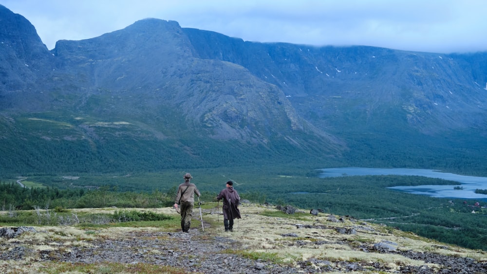 a couple of people walking on a path in front of a lake