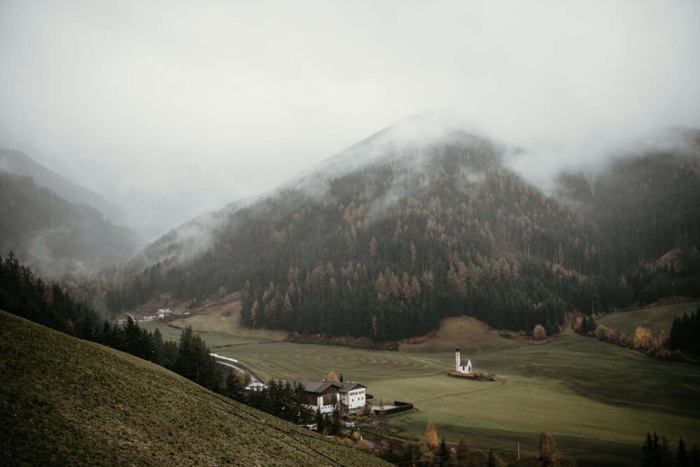 a house on a hill with trees and mountains in the background