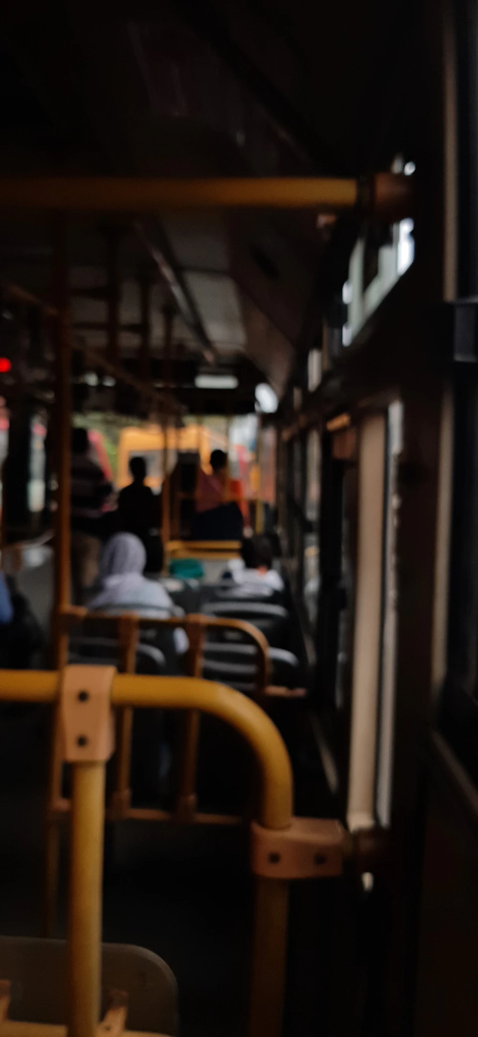 Passengers seated on benches or standing near doors gaze out windows in urban setting