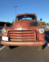 A classic rusted 1950s pickup truck parked on a gravel lot under a wide Montana sky.