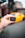 A hand is holding a small black device labeled 'BlueDriver,' with a blurred background that includes a bright yellow sports car.