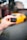A hand is holding a small black device labeled 'BlueDriver,' with a blurred background that includes a bright yellow sports car.