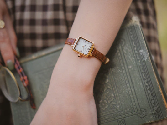 Vintage-inspired fossil brynn 30mm gold-tone watch placed next to classic sunglasses and a leather notebook.