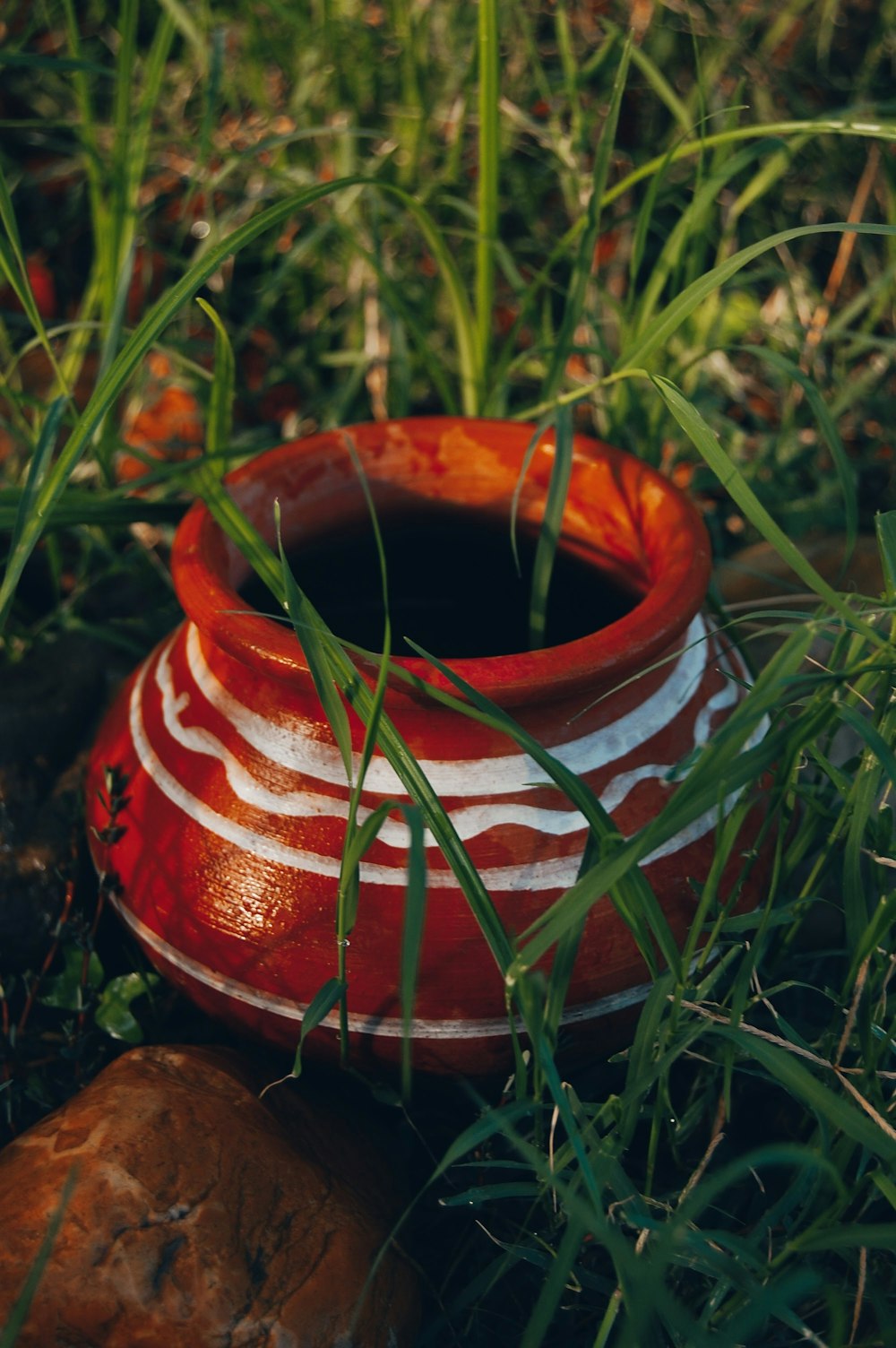 a red and white pot in the grass